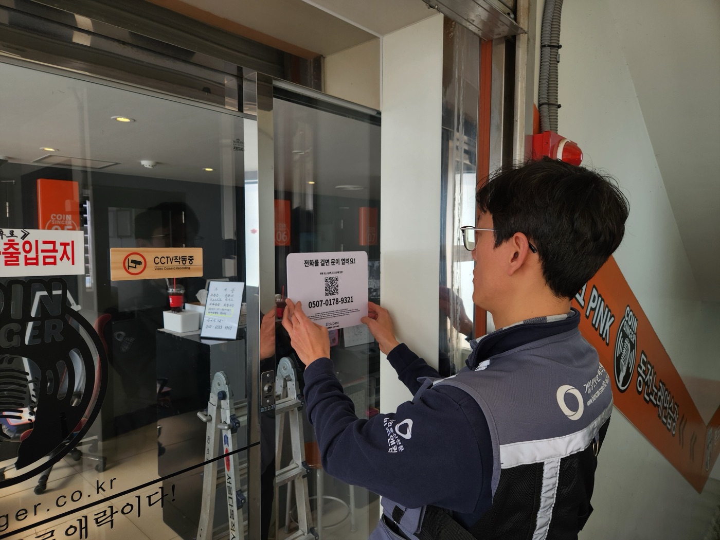 코인노래방 출입문에 BizPass 안내 스티커 부착